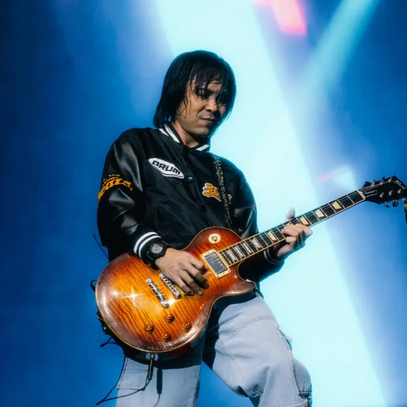 Pop singer wearing a trendy jacket plays music on guitar on stage